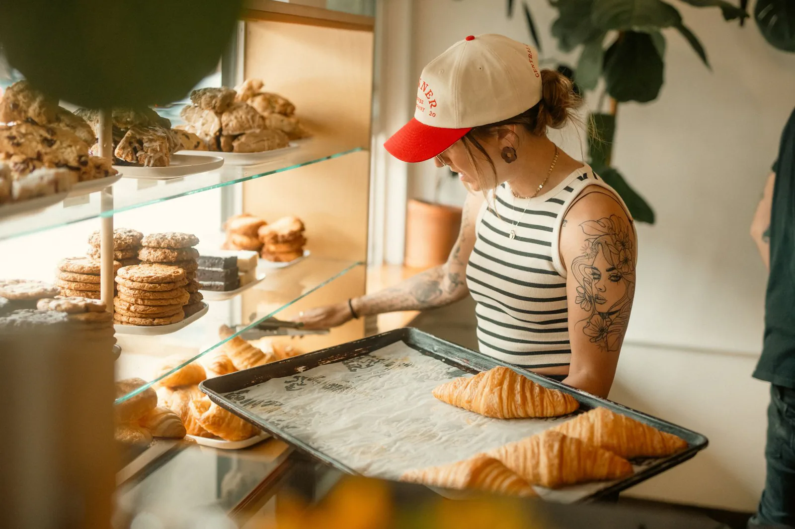 Pastry chef arranging croissants in bakery display case